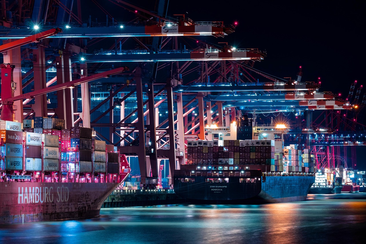 Porto industrial à noite com guindastes e navios de contêineres